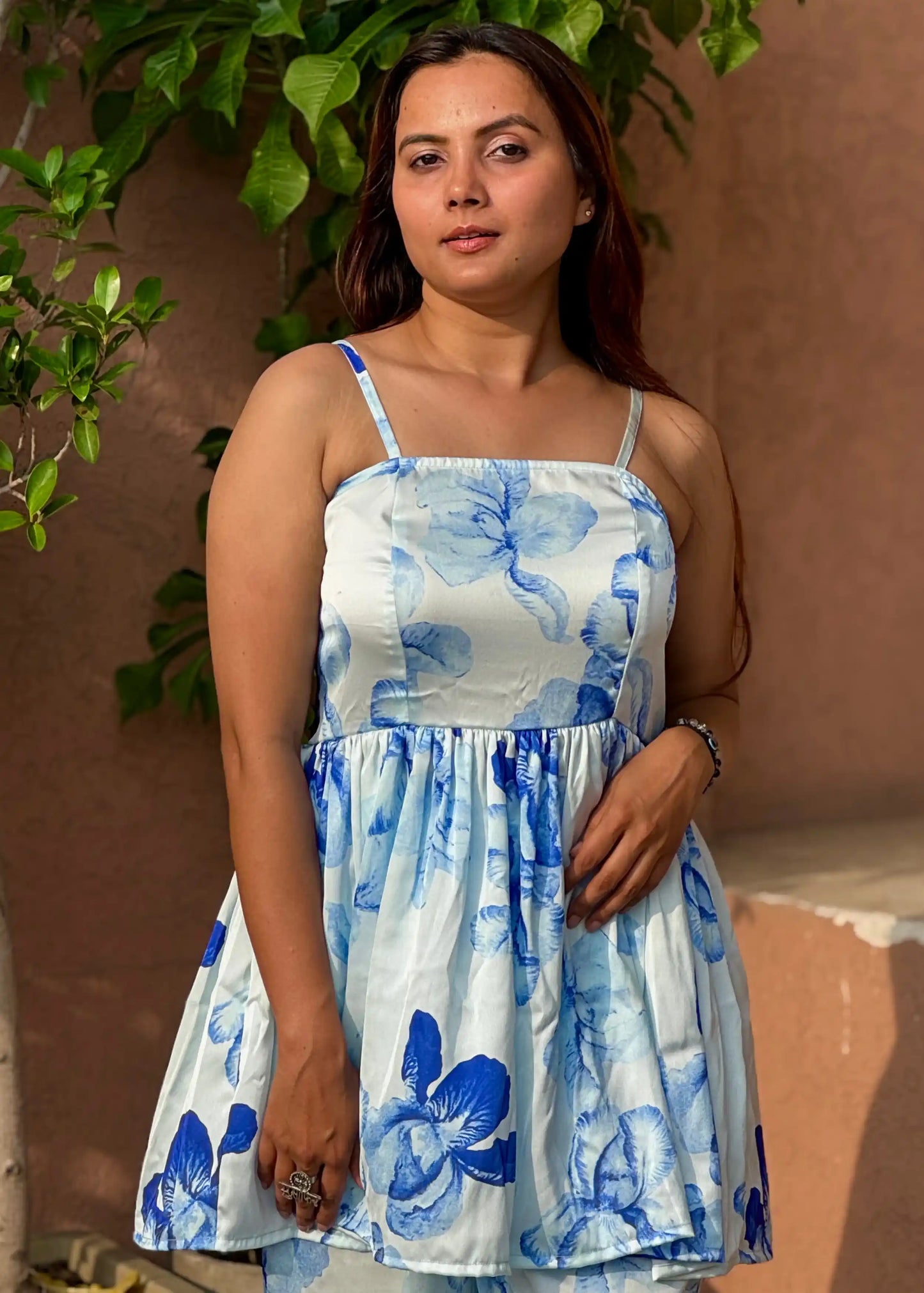 White mini dress with blue floral print, sleeveless design, gathered waist, soft cotton women’s wear by An-Attire.