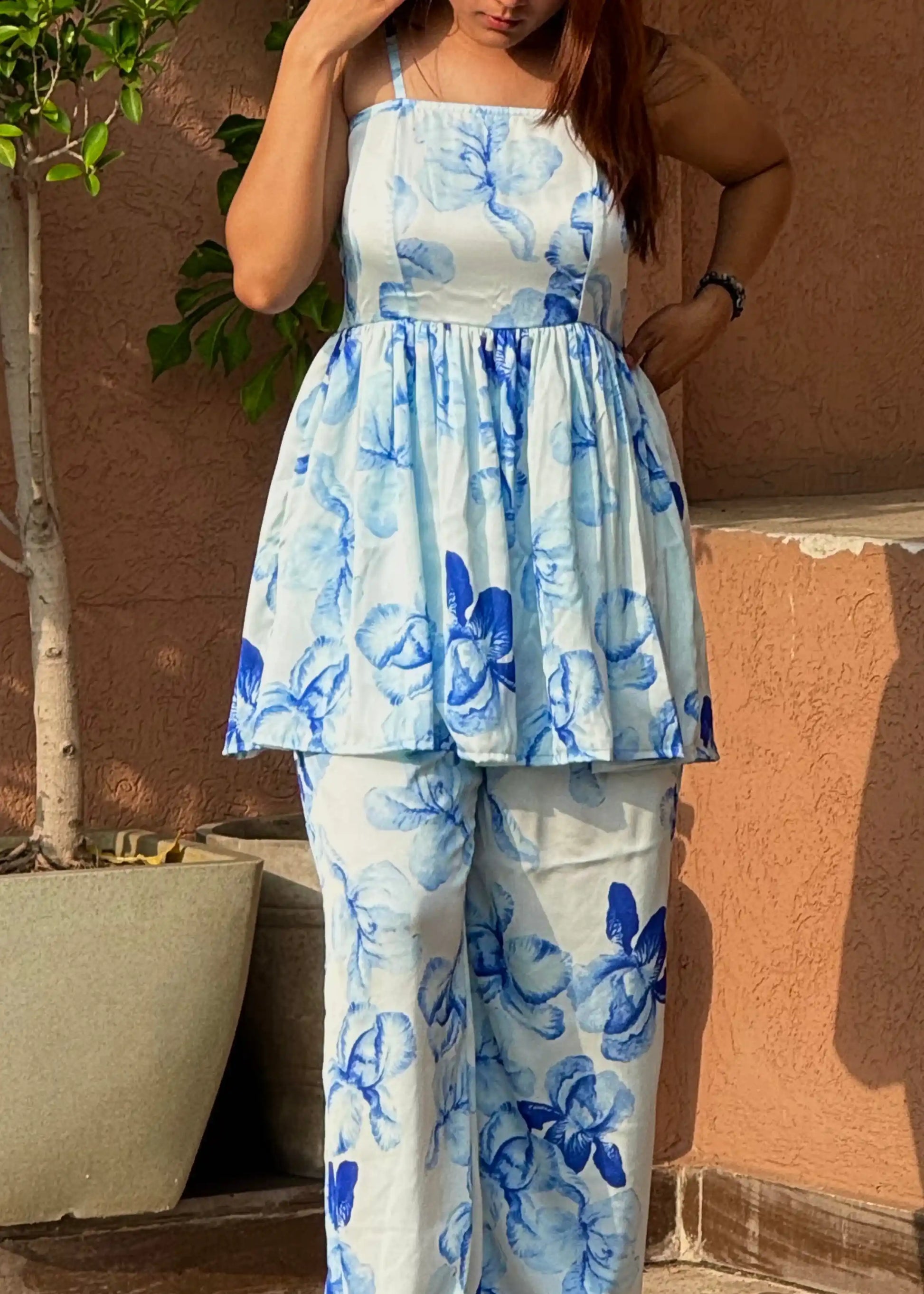 White mini dress with blue floral print, sleeveless design, gathered waist, soft cotton women’s wear by An-Attire.